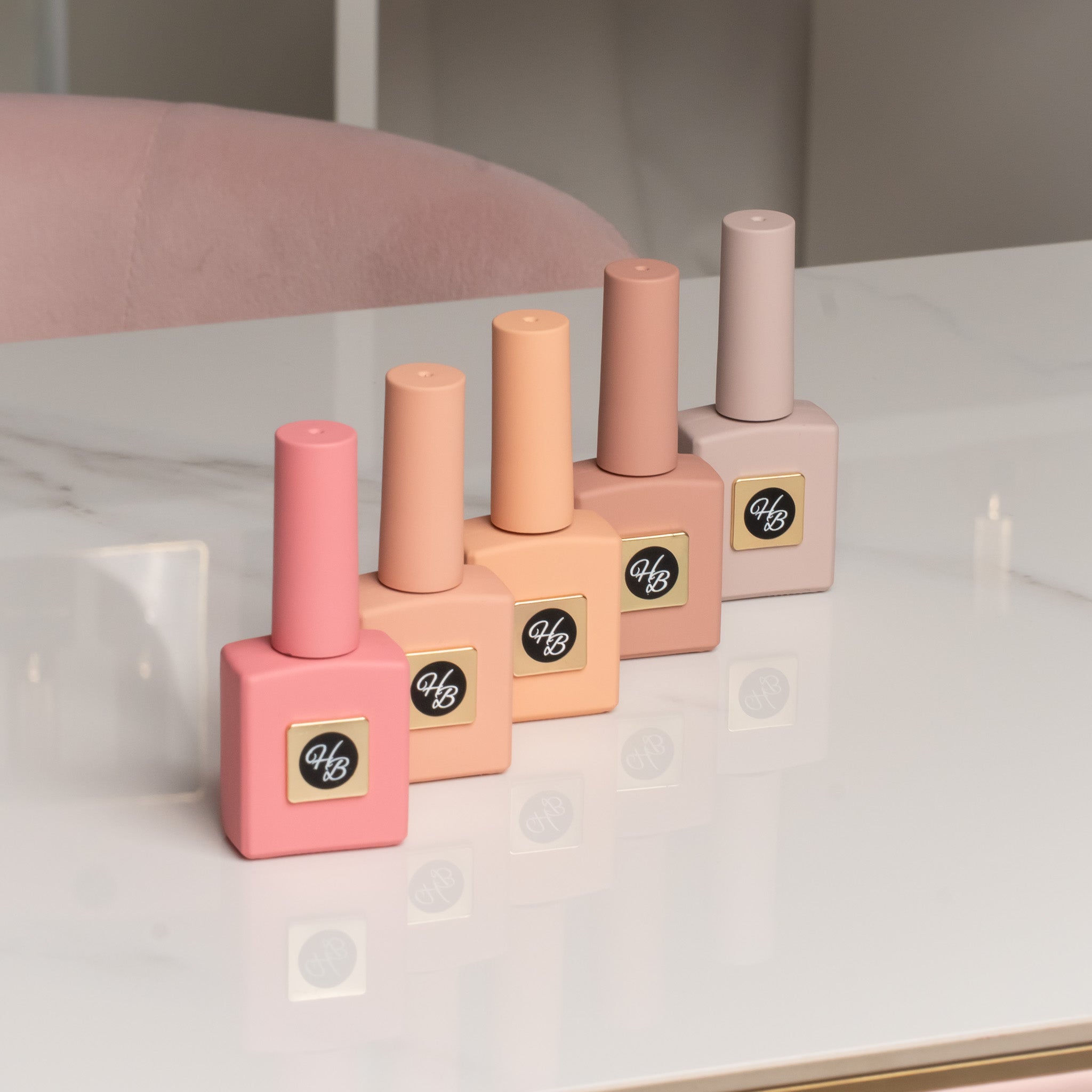 Hand holding HEMA-Free gel polish swatches in peach, nude, and natural pinks