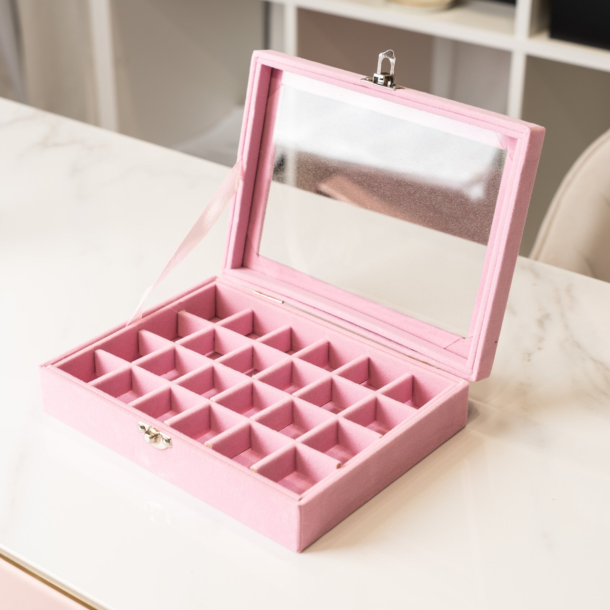 Pink jewelry box with compartments on a light surface