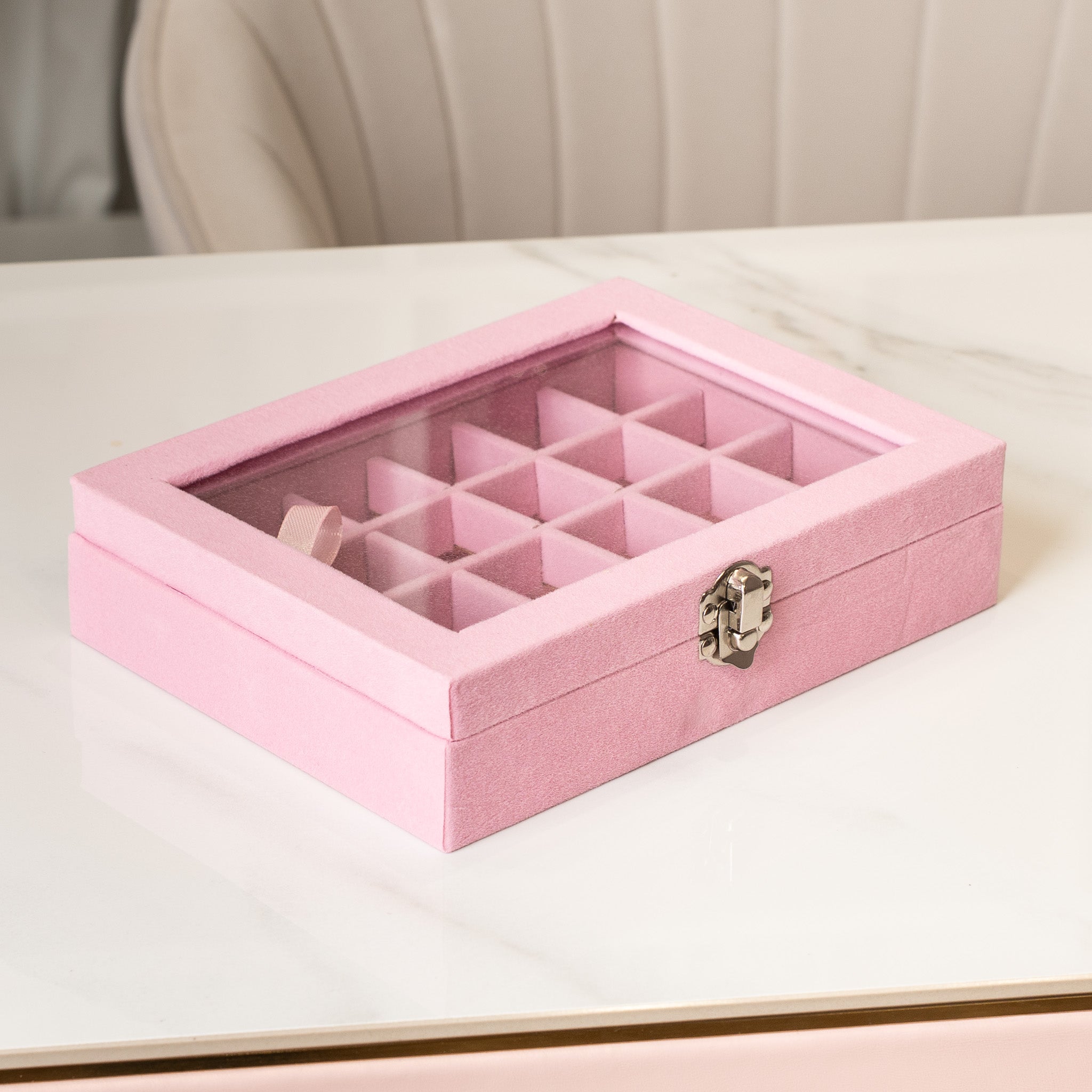 Pink jewelry box with compartments on a light surface