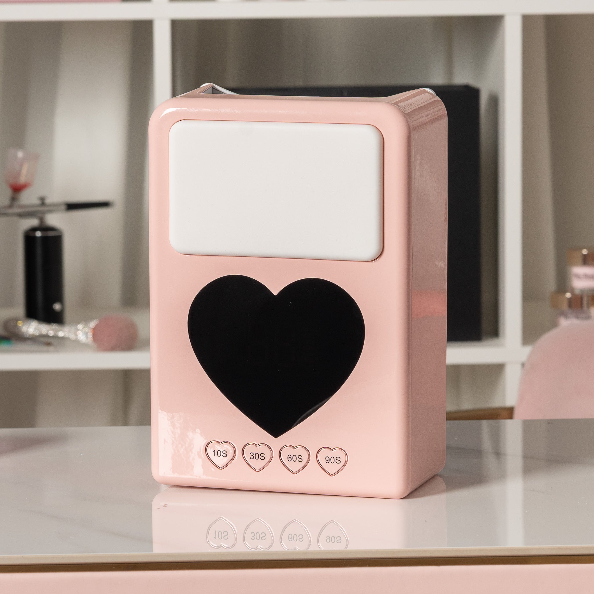 Pink electronic device with a heart symbol on a white surface