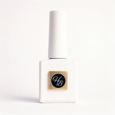 White nail polish bottle with gold and black label on a white background